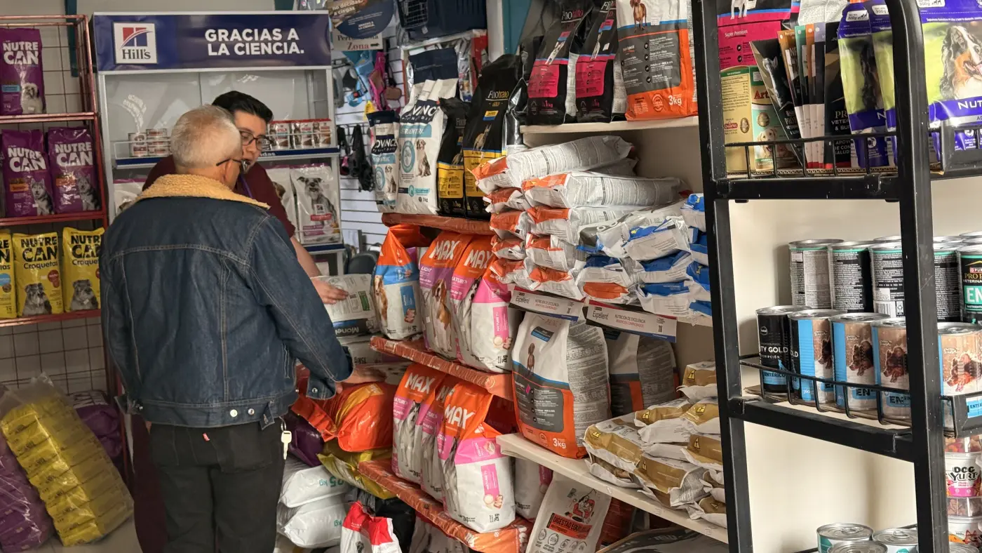 Un integrante del equipo de Mascott asesorando a un cliente frente a las estanterías de alimento para perros y gatos